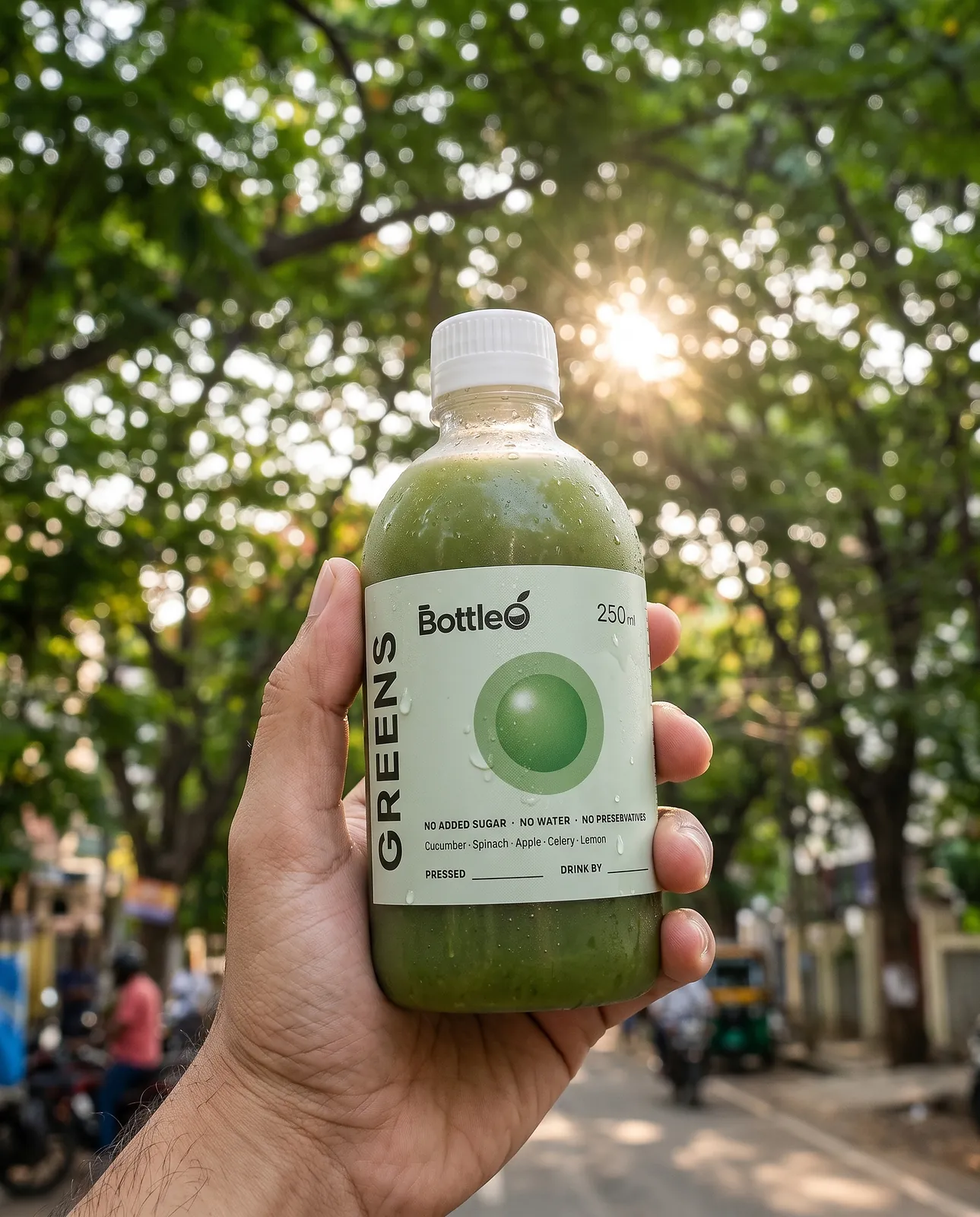 A hand holding a cold bottle of BottleO Greens outdoors